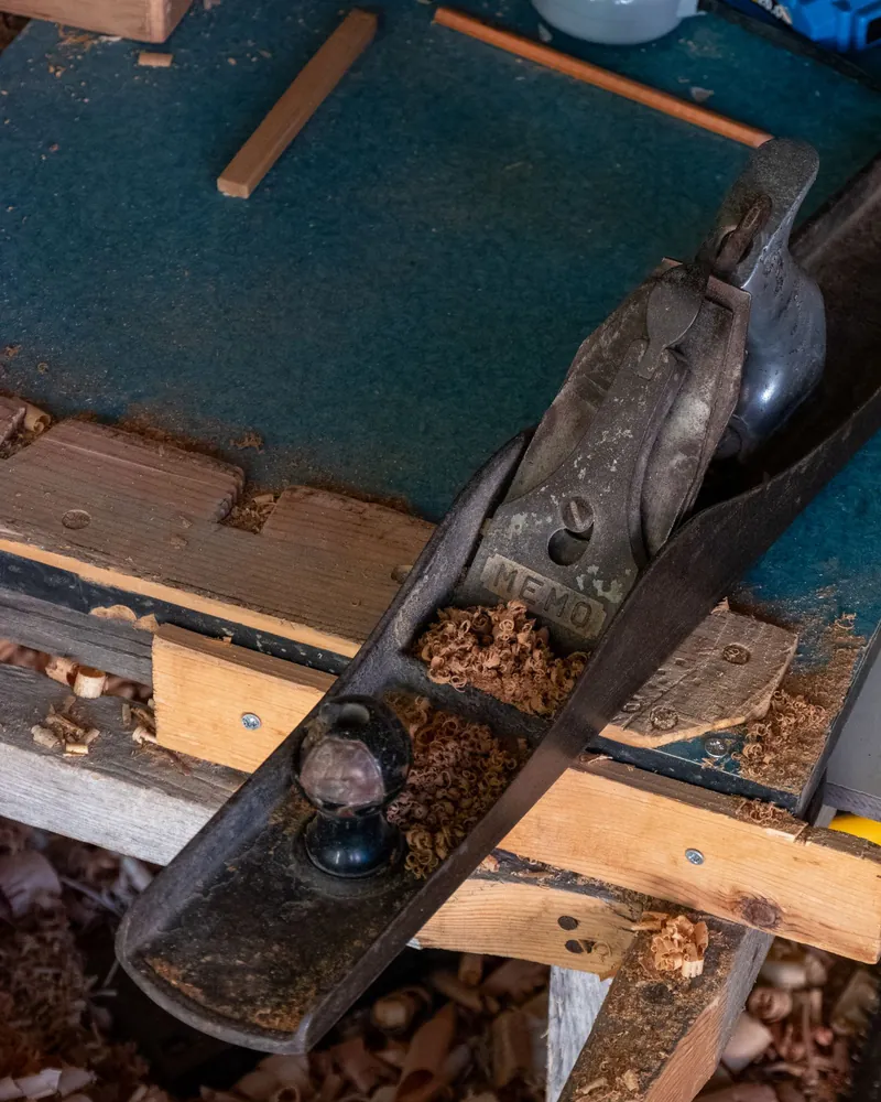 Cepillo de mano apoyado en un banco de carpintero entre virutas de madera